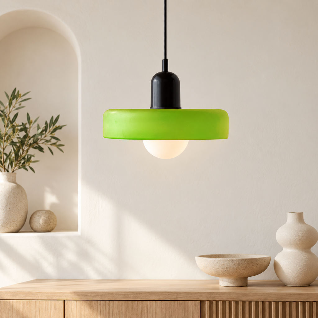 Pendant light with matte green disc shade and black body in a bright interior